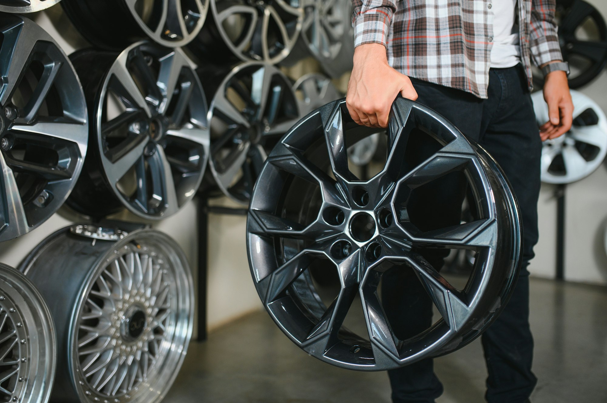 male customer choosing alloy wheel rims at car repair service or auto store